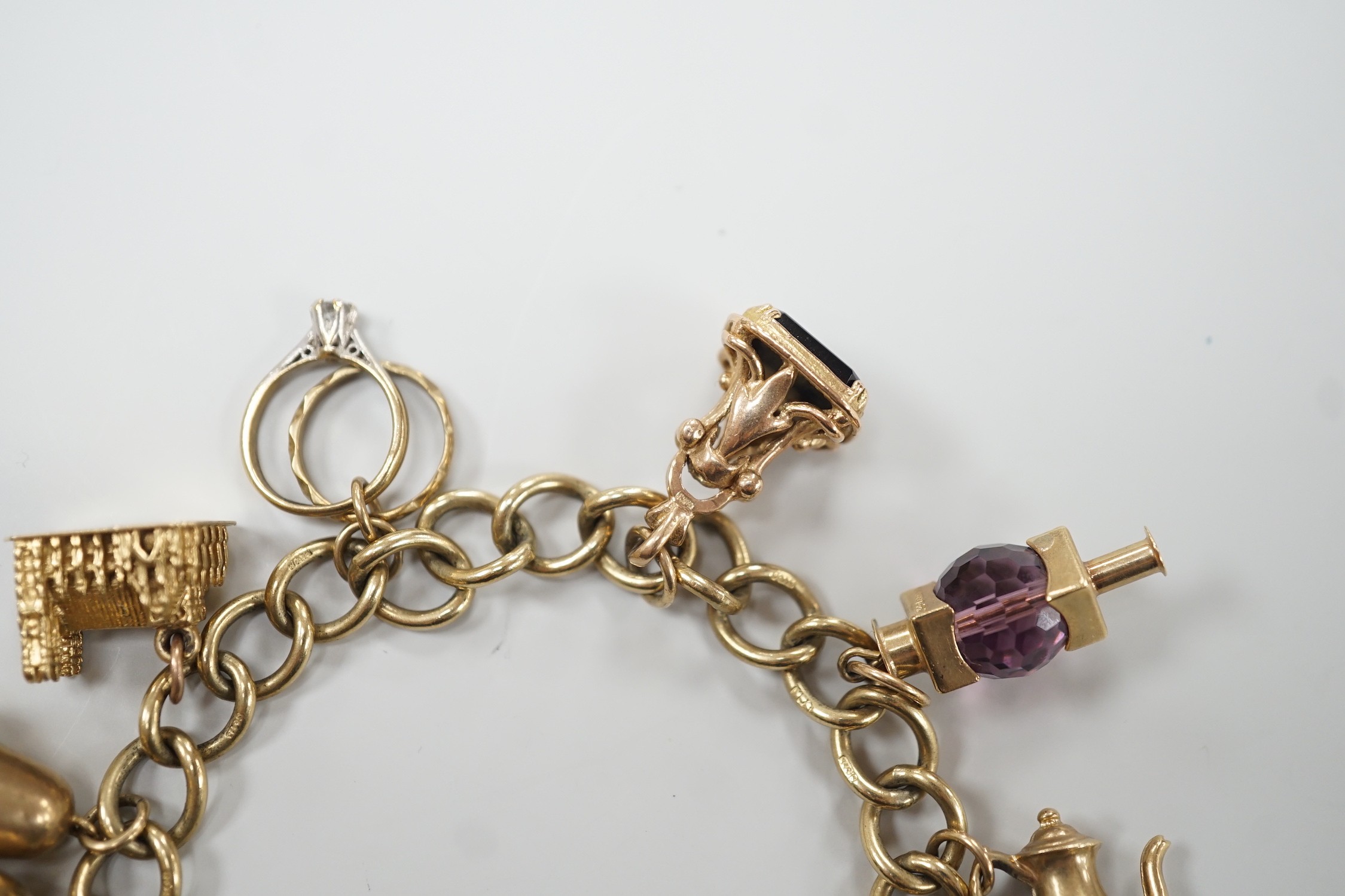 A 9ct gold oval link charm bracelet, hung with ten assorted charms including nine 9ct gold, gross weight 31.9 grams.